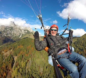 Tandem paragliding over Salzburg with mountains and forest in the background
