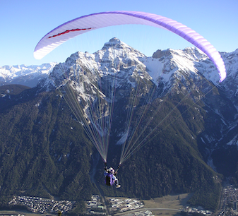 Paragliding in Innsbruck with snowy Alpine peaks in the background