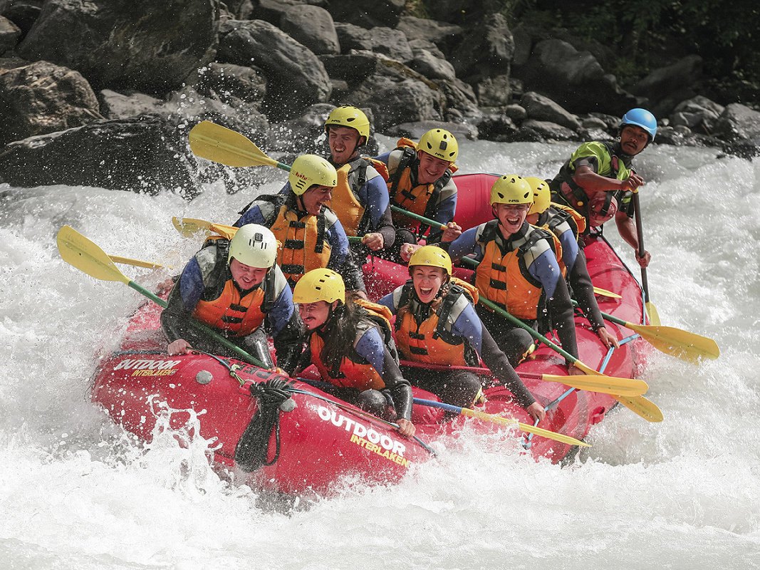 White water rafting in Interlaken, Switzerland with a group navigating fast rapids on an alpine river.