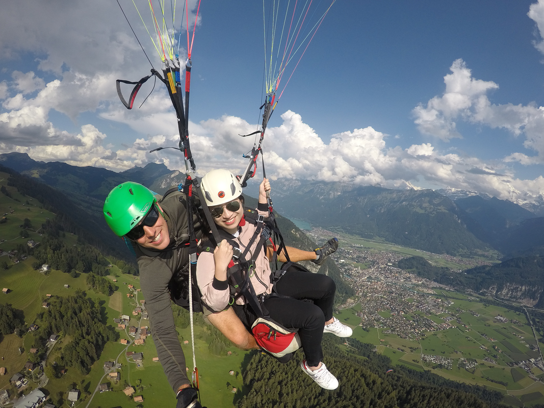 Tandem paragliding in Interlaken, Switzerland with panoramic views over the valley, lakes, and Swiss Alps.