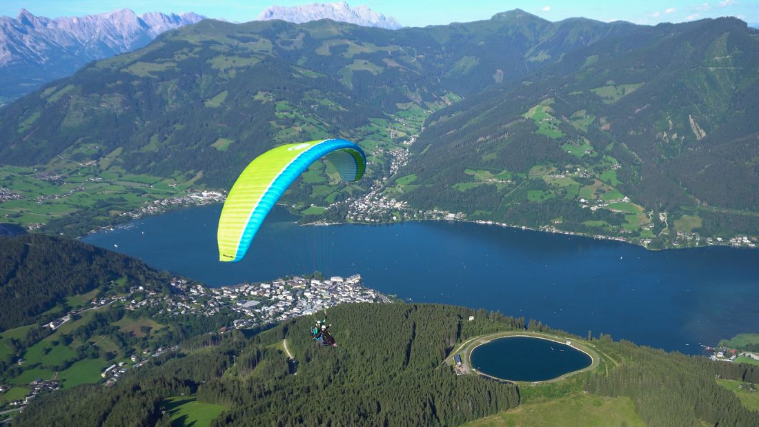 Paragliding in Zell am See, Austria with panoramic views over the lake, alpine towns, and surrounding mountain valleys.